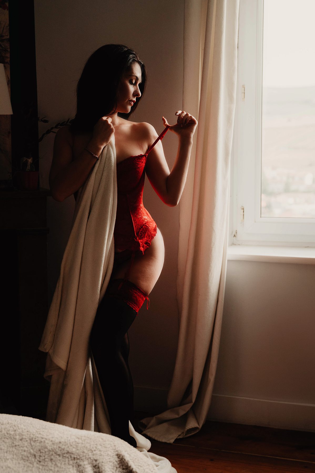 Femme en lingerie à contre-jour devant une fenêtre, lumière chaude